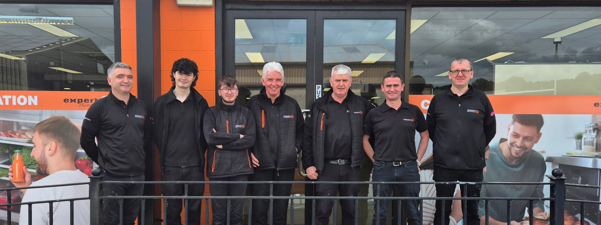 Team of people in front of a store with an 'Irwin Electrical Expert' sign.